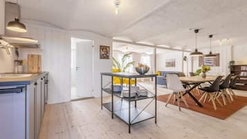 A modern kitchen with white cabinetry, a wooden countertop, and a dining area with a table and chairs.