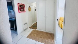 A hallway with white walls, a ceiling fan, a door, a small rug, and a yellow chair. - Comfortable apartment near the center - 4 guests (Amélie-les-Bains-Palalda)