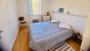 A bedroom with a bed, a chair, a desk, a window, and a shelf with items. - Comfortable apartment near the center - 4 guests (Amélie-les-Bains-Palalda)