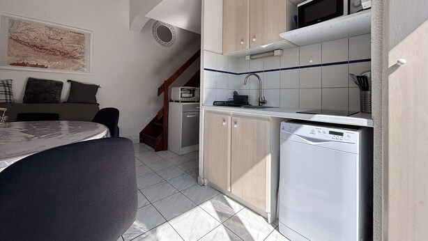 Een kleine keuken met een magnetron, vaatwasser en een klein spoelbakje.