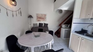Een kleine keuken met een eethoek, een kaart aan de wand en een trap naar een verdieping erboven.