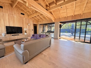 Un espacio habitable amplio con un sofá grande, un televisor de pantalla plana y un techo de madera.