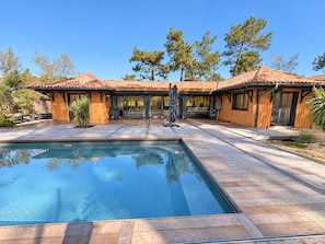 Una casa moderna con piscina, fachada de madera y amplios ventanales.