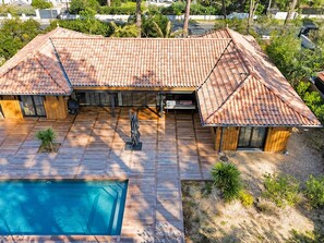 Una casa de dos pisos con techo de tejas, piscina y zona de patio.