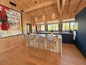 Une cuisine moderne avec un coin bar, un plafond en bois et de grandes fenêtres.