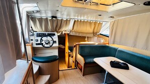 A compact interior with a steering wheel, a table, and a cushioned seating area.