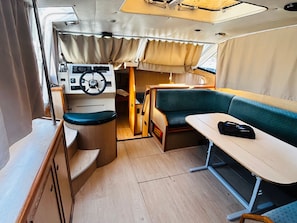 A compact interior with a steering wheel, a table, and a cushioned seating area.