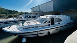 A marina with several boats docked, a large building in the background, and a clear sky.