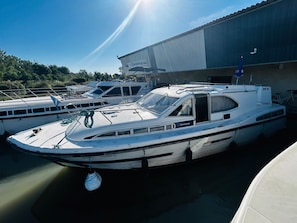 A marina with several boats docked, a large building in the background, and a clear sky.