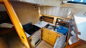 A compact kitchenette with a stove, oven, sink, and storage cabinets.