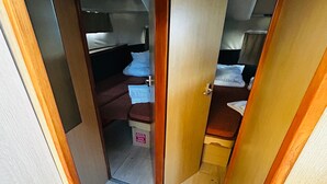 A narrow corridor leading to a bedroom with a bed, a small table, and a bench.