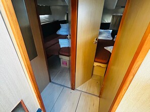 Un couloir étroit mÚne à une chambre à coucher qui contient un lit, une petite table et un banc.