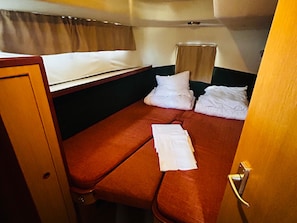 A compact cabin with a bunk bed, a small window with curtains, and a door with a handle.