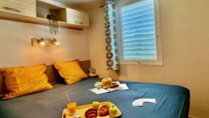 Ein Hotelzimmer mit einem Bett, einem Tablett mit Frühstücksangeboten und einem Fenster mit Jalousien.