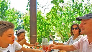 Eine Familie isst draußen und hat Pizza, Salat und Getränke auf dem Tisch.