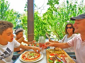 A family dining outdoors with a pizza, salad, and drinks on the table. - Mobile home with terrace - 5 guests (Saint-Astier)