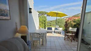 Un balcón con mesa, sillas, un paraguas amarillo y un cartel que dice 'Côte Terrasse'.