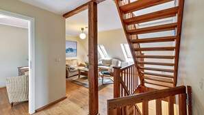 A loft-style room with a wooden staircase, a sofa, a coffee table, and a view of the outdoors.