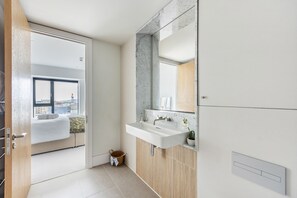 Ein modernes Badezimmer mit einem großen Waschbecken, einem Spiegel und Blick auf einen Balkon.