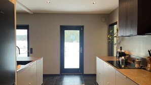 A modern kitchen with a black countertop, a built-in oven, and a stainless steel sink. - Waterfront villa with private dock & wood-fired sauna in nature reserve (Saltsjö-Boo)