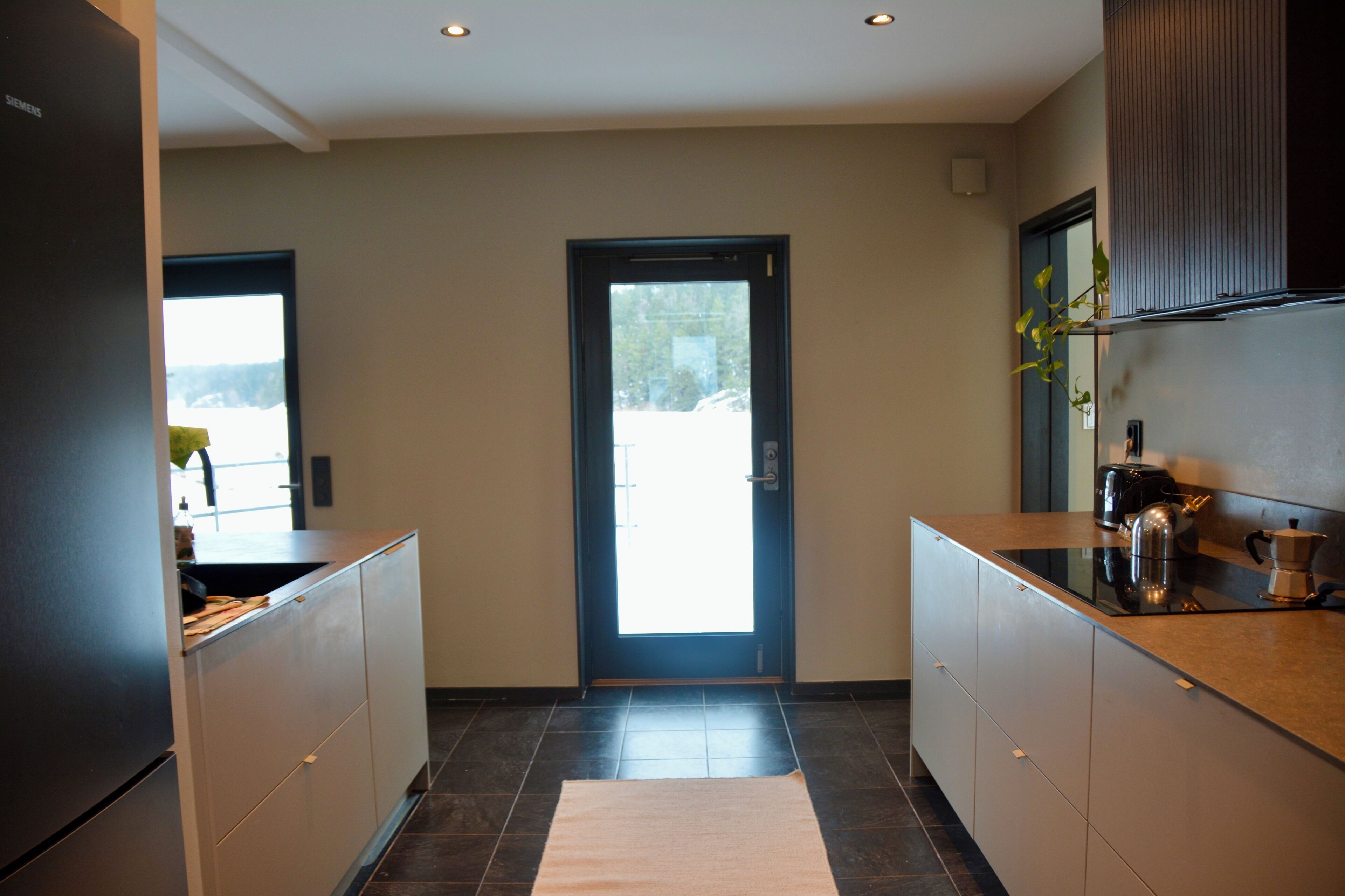 A modern kitchen with dark cabinets, a stainless steel refrigerator, and a coffee maker on the counter.