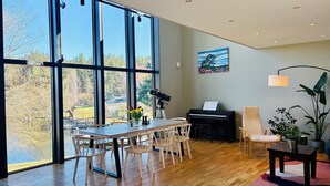 A spacious room with large windows, a piano, a telescope, and a painting. - Waterfront villa with private dock & wood-fired sauna in nature reserve (Saltsjö-Boo)