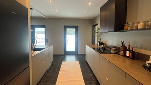 A modern kitchen with a refrigerator, stove, and countertop. - Waterfront villa with private dock & wood-fired sauna in nature reserve (Saltsjö-Boo)