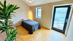 A bedroom with a bed, a potted plant, a window, and a door leading to a balcony. - Waterfront villa with private dock & wood-fired sauna in nature reserve (Saltsjö-Boo)