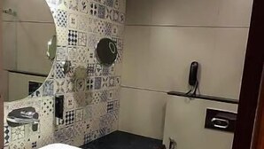 A bathroom with a white sink, a mirror, a toilet, and patterned tiles on the walls. - SKY PENTA RESIDENCY (Iritty)