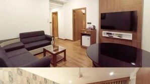 A hotel room with a bed, a sofa, a TV, and a desk. - SKY PENTA RESIDENCY (Iritty)