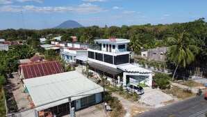 A hotel with a modern design, a prominent 'HOTEL' sign, and a view of a mountain in the background. - Ngoc An Hotel (Long Hoa)
