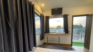 A bedroom with a bed, a desk, a TV, and a balcony with a view. - Ngoc An Hotel (Long Hoa)
