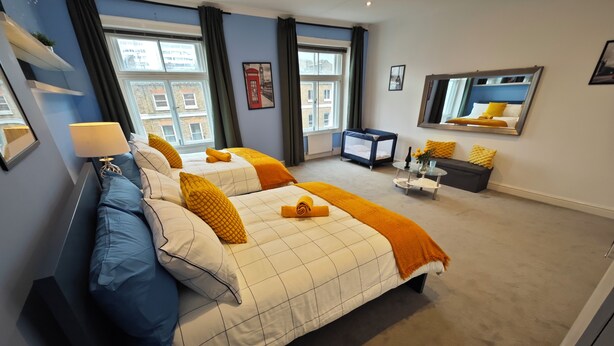 Ein Hotelzimmer mit zwei Betten, einem Schreibtisch, einem Stuhl, einem kleinen Tisch und einem großen Fenster.