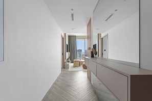 Ein moderner Hotelkorridor mit Fischgrätparkett, einem großen Spiegel und Blick auf die Stadt durch ein Fenster.