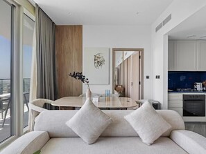 Ein modernes Wohnzimmer mit Sofa, Esstisch und Blick auf die Stadt.