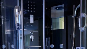 A modern spa room with a glass-enclosed hot tub, control panel, and shower area. - Modern SPA studio in the heart of Gehrden (Gehrden)