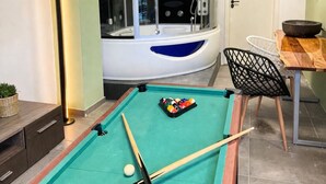 A pool table with balls and cues, a chair, a small table with a bowl, and a door. - Modern SPA studio in the heart of Gehrden (Gehrden)
