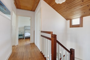 Un couloir doté d’un plancher en bois, de murs blancs et d’un plafond en bois.