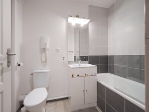 A bathroom with a toilet, sink, mirror, and bathtub. - Saint Clair Ndeg318 - ST3 (Agde)