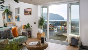 Un salon moderne offrant une vue sur un paysage montagneux grâce à de grandes portes vitrées.