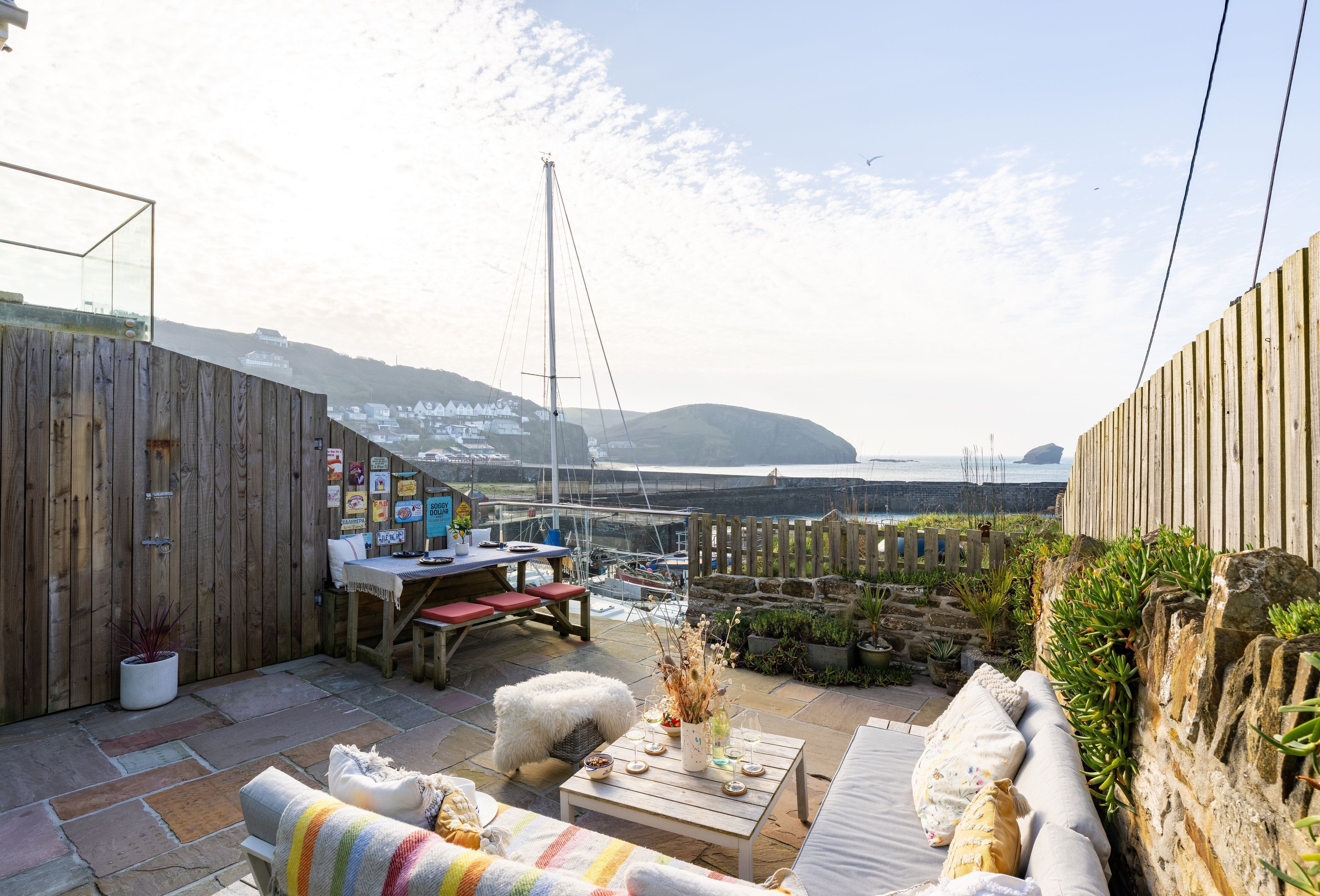 Une terrasse avec une clôture en bois, une table et un canapé.
