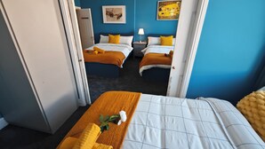 A hotel room with two beds, a blue wall, and a painting. - Luxury 4-Bedroom Apartment near Oxford St/ Baker Street (London)