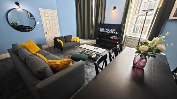 A living room with a sofa, coffee table, TV, and a dining table with chairs. - Luxury 4-Bedroom Apartment near Oxford St/ Baker Street (London)