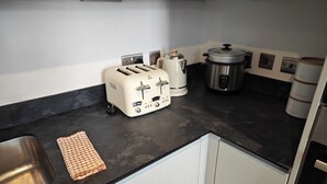 A kitchen with a sink, a checkered cloth, a toaster, a kettle, a pressure cooker, and a coffee maker. - Luxury 4-Bedroom Apartment near Oxford St/ Baker Street (London)