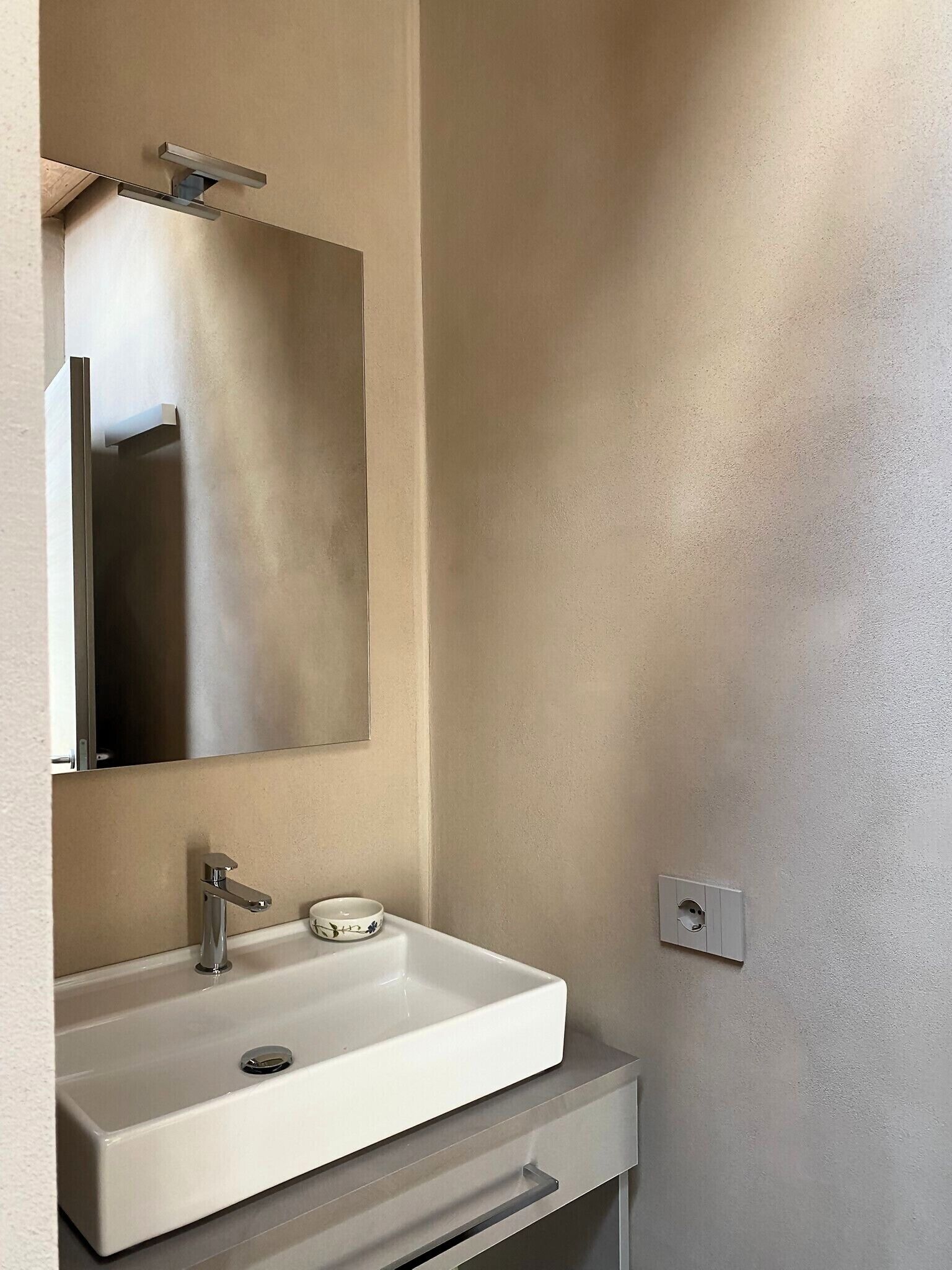 Een badkamer met een witte wastafel, een spiegel en een handdoekhouder.