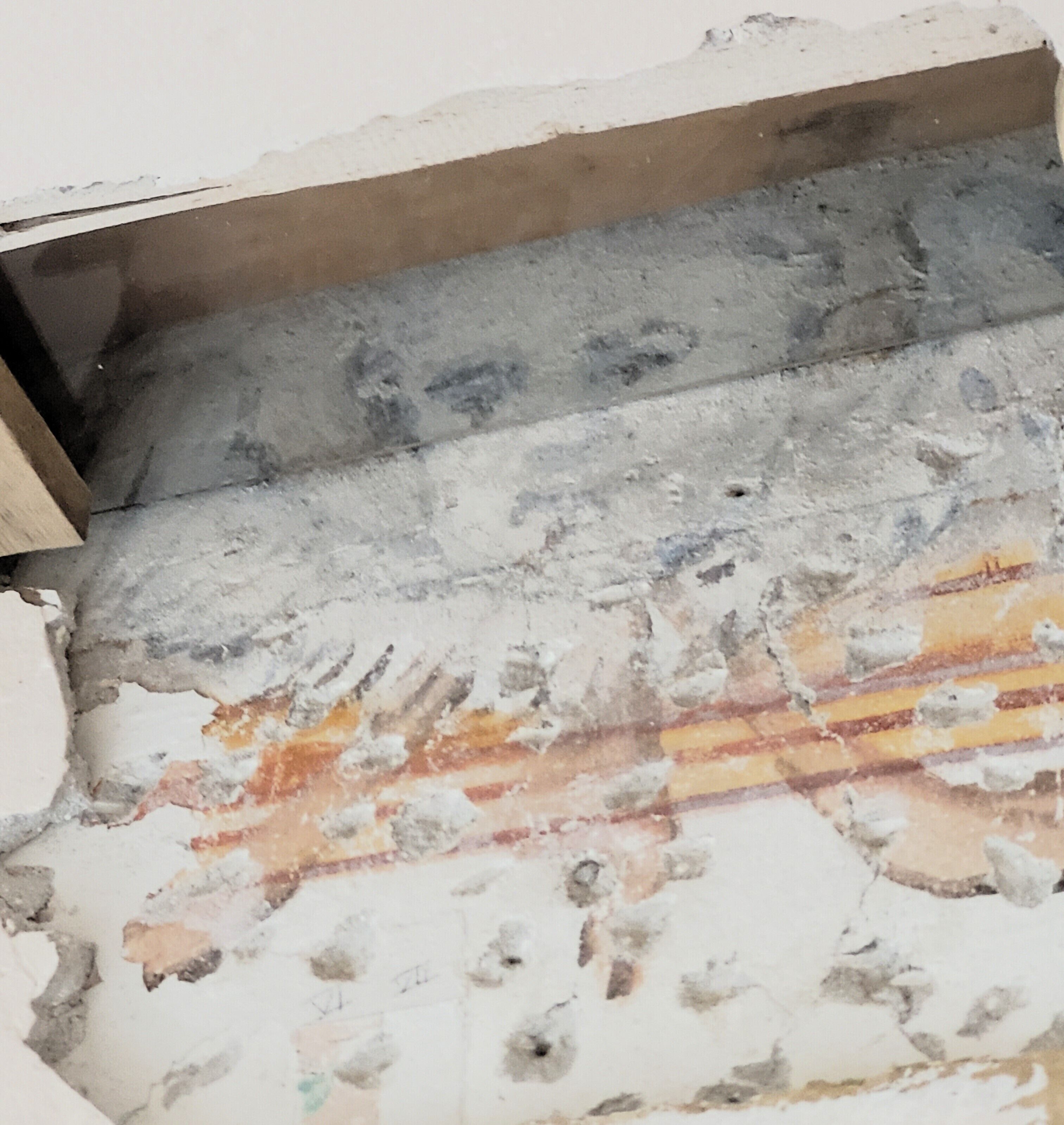 Primer plano de una pared con pintura descascarada y ladrillo a la vista.