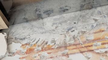 Primer plano de una pared con pintura descascarada y ladrillo a la vista.