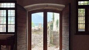 Une pièce dotée d’un sol carrelé en pierre, de murs en bois et d’une grande porte en arc donnant sur l’extérieur.