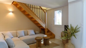 A living room with a wooden staircase, a sofa, a small table, and a plant. - Charming Duplex 500m from the port (Hyères)