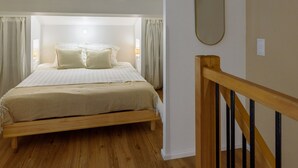 A bedroom with a wooden bed, a wooden staircase, and a mirror on the wall. - Charming Duplex 500m from the port (Hyères)